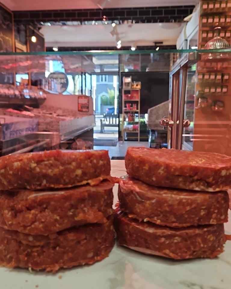 Hand-pressed burger patties in the Market Fair counter, with the shop floor and grocery shelves behind